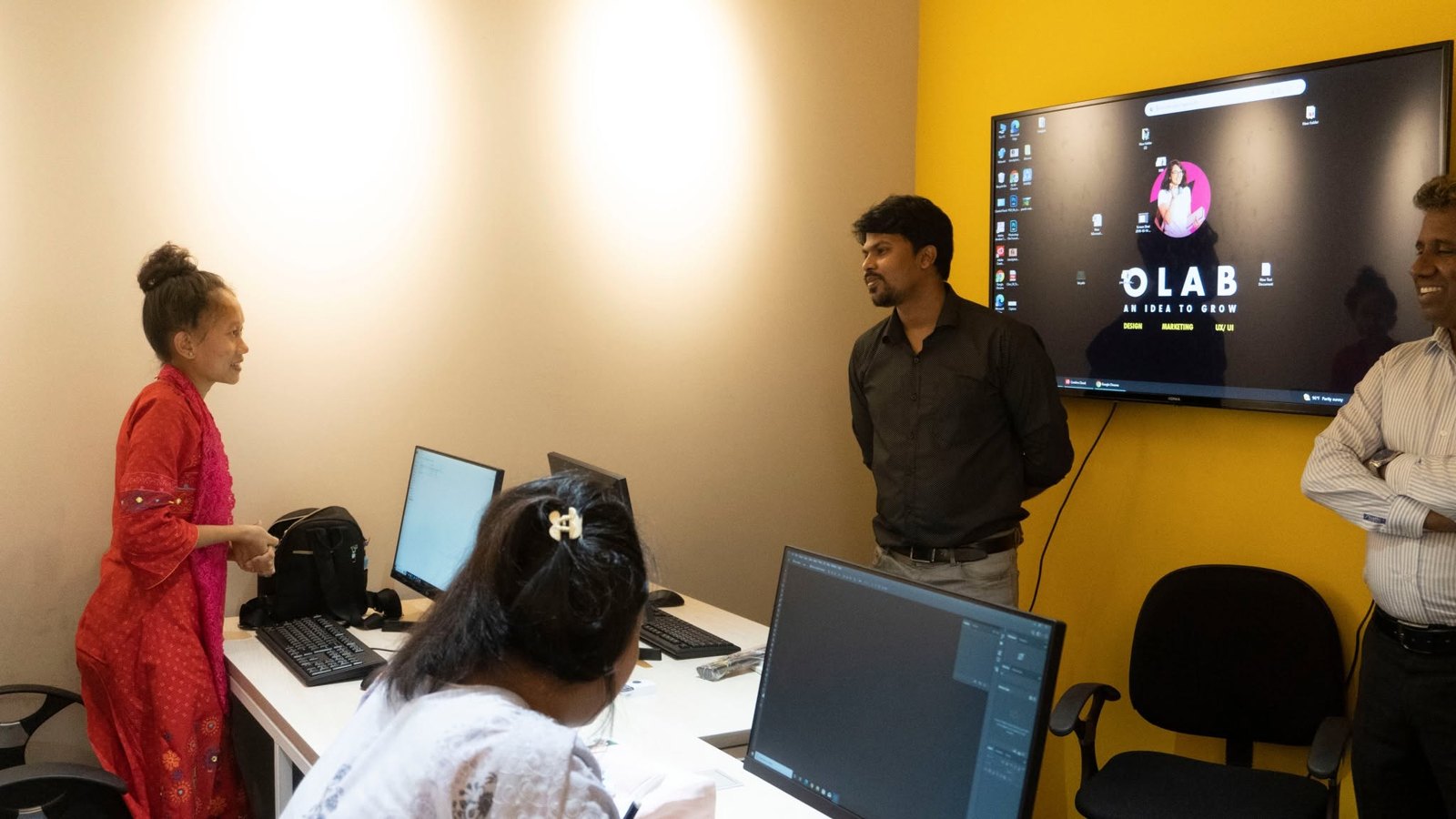 Staff and learners in an OLab-branded training room with the logo on a wall display