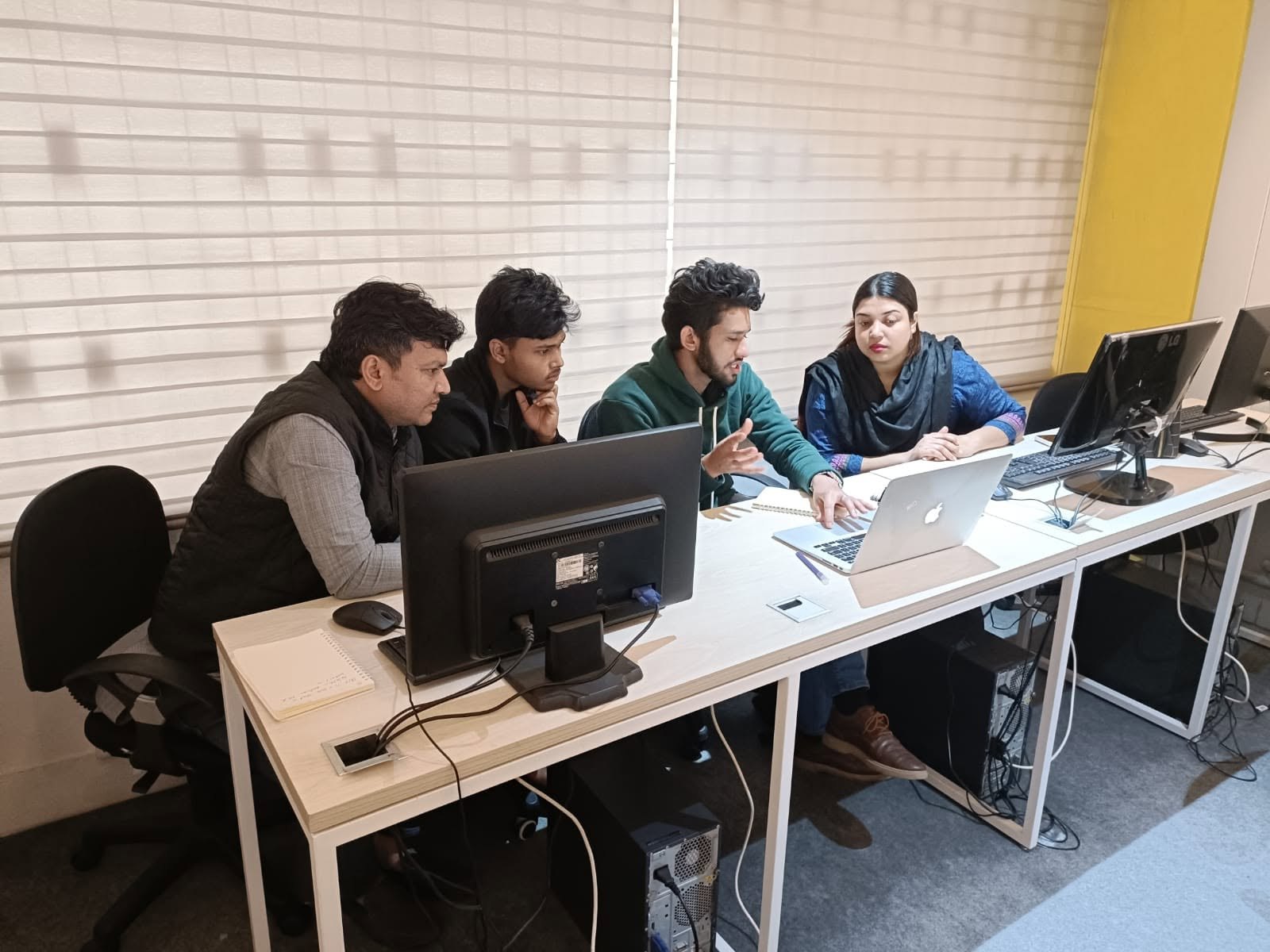 Four colleagues gathered around a laptop in the OLab office reviewing work