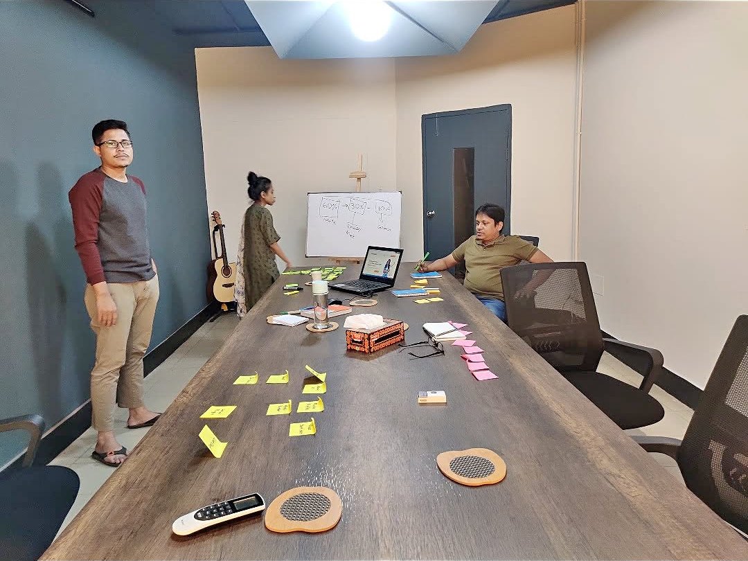A team ideating around a table with sticky notes and a whiteboard